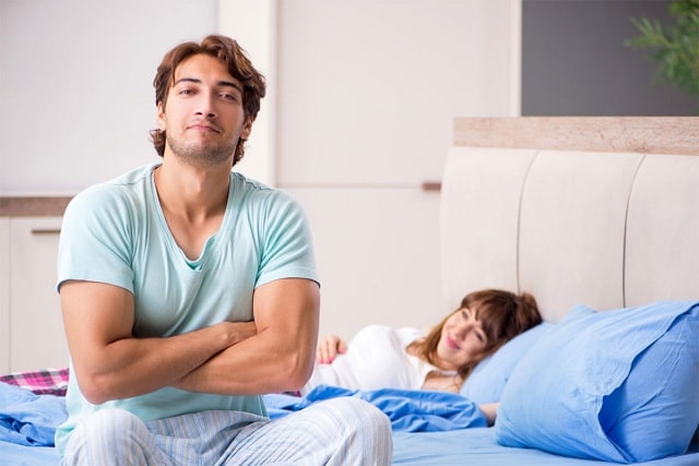 Man sitting on bed and woman lying down on bed