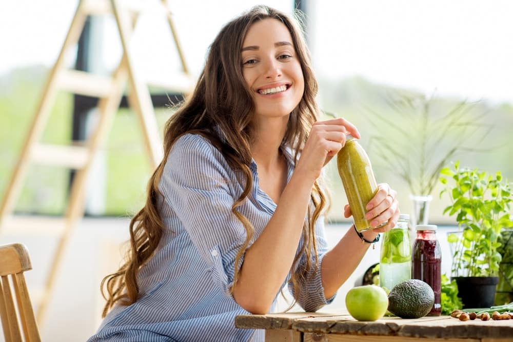 Woman smiling and holing detox drink