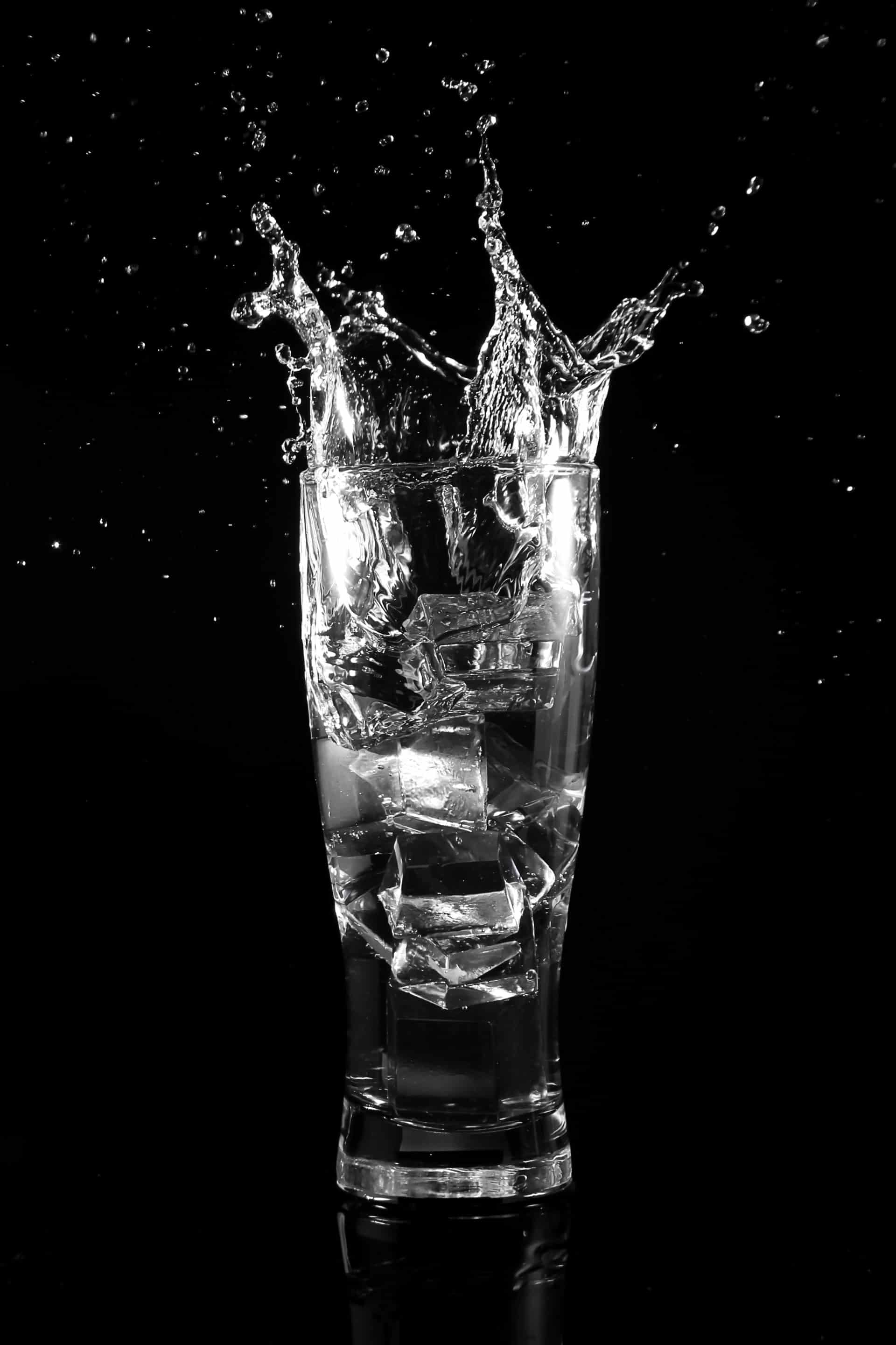 Glass of ice water scattered on a black background