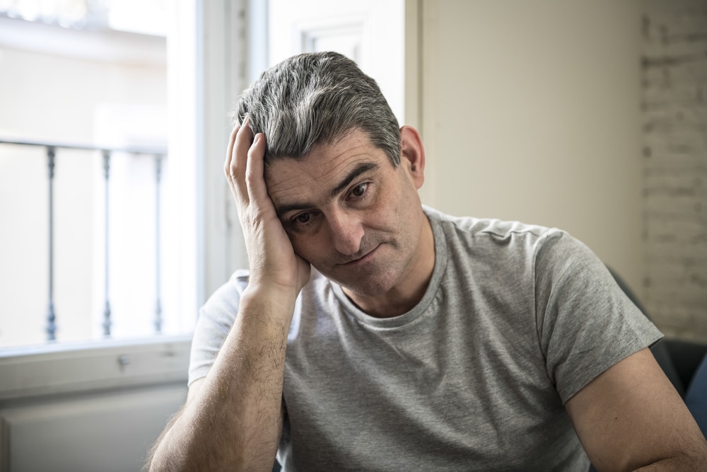 worried man with grey hair sitting at home couch looking depressed and wasted in sadness face expression in depression and life problems concept