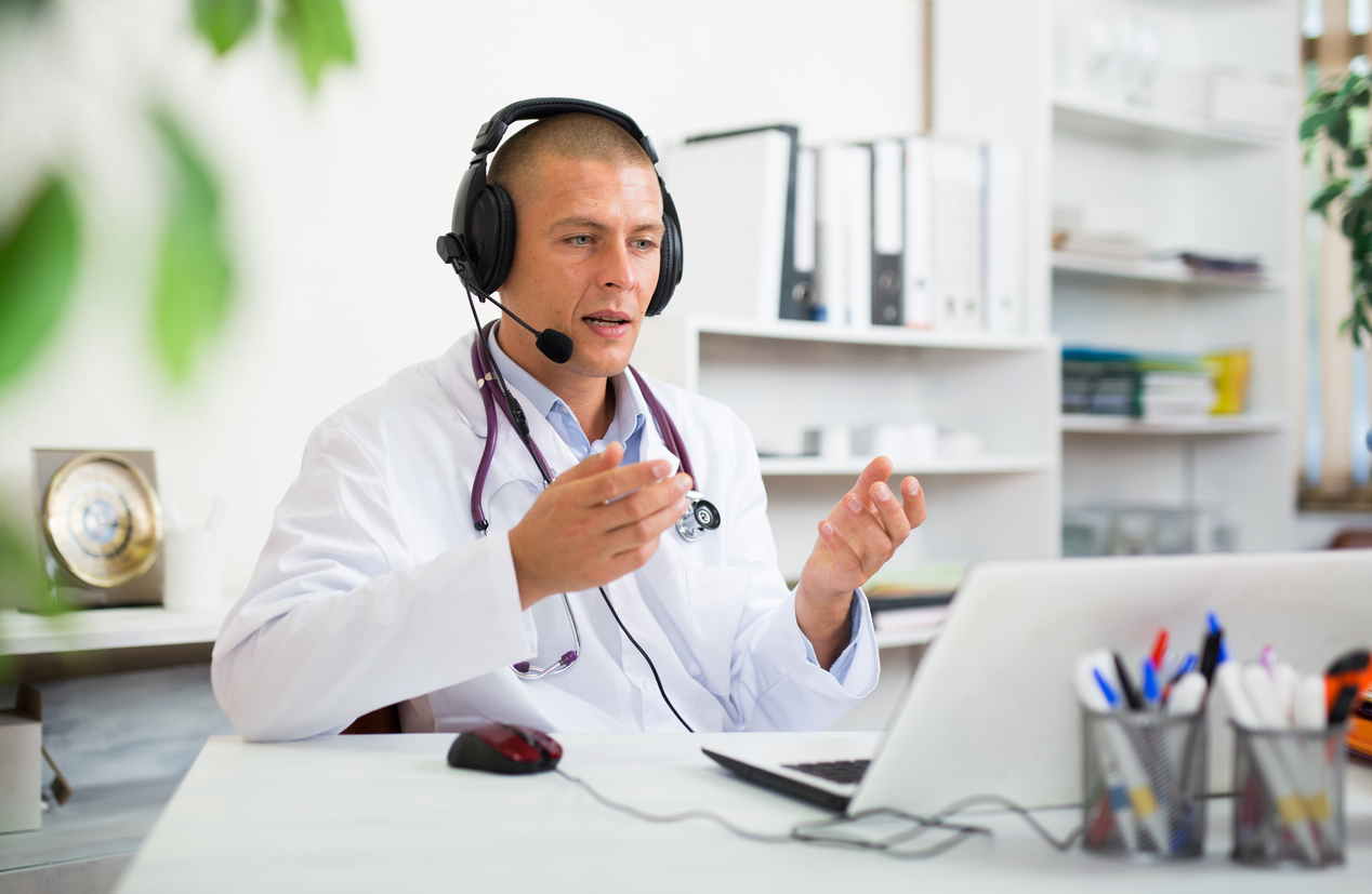 Doctor in earphones having online consultation with patient on laptop stock photo