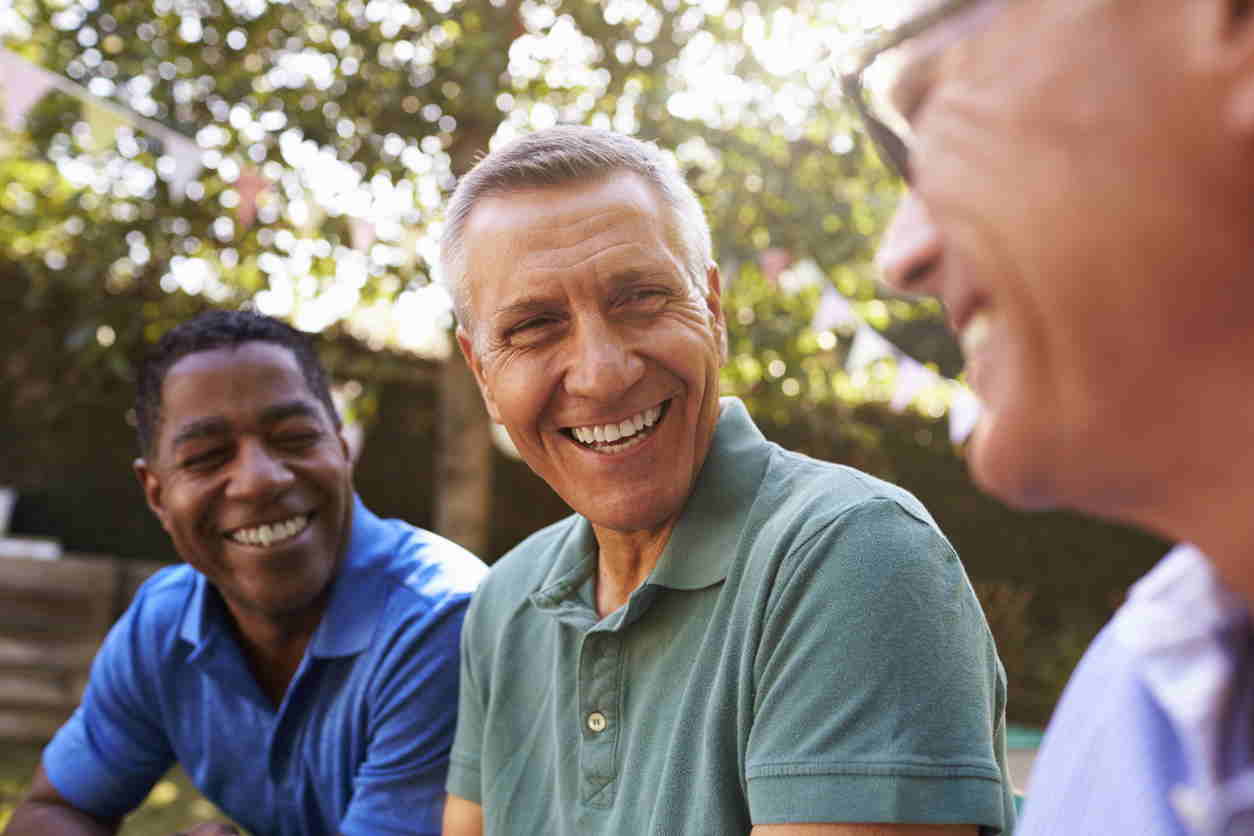 Mature Male Friends Socializing In Backyard Together stock photo