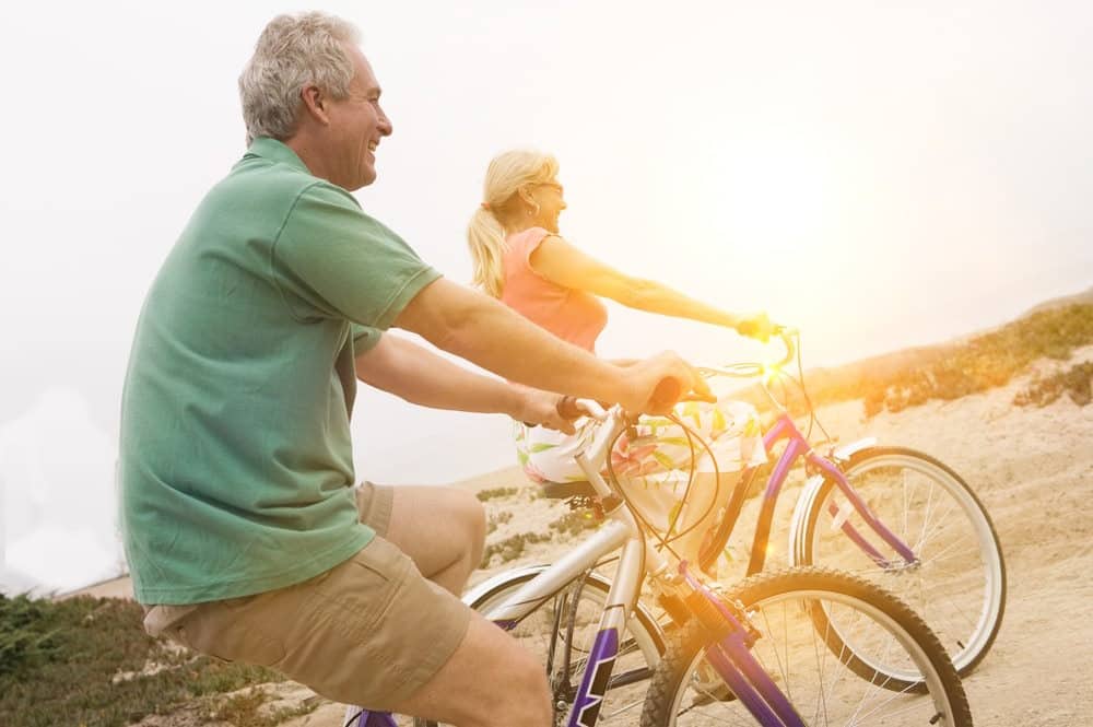 Middle aged couple riding bicycles with lens flare