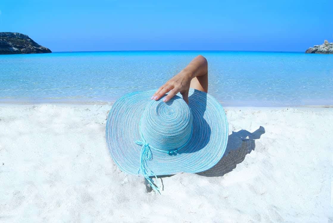 girl-in-a-beach-hat-lying-down-in-beach-sand