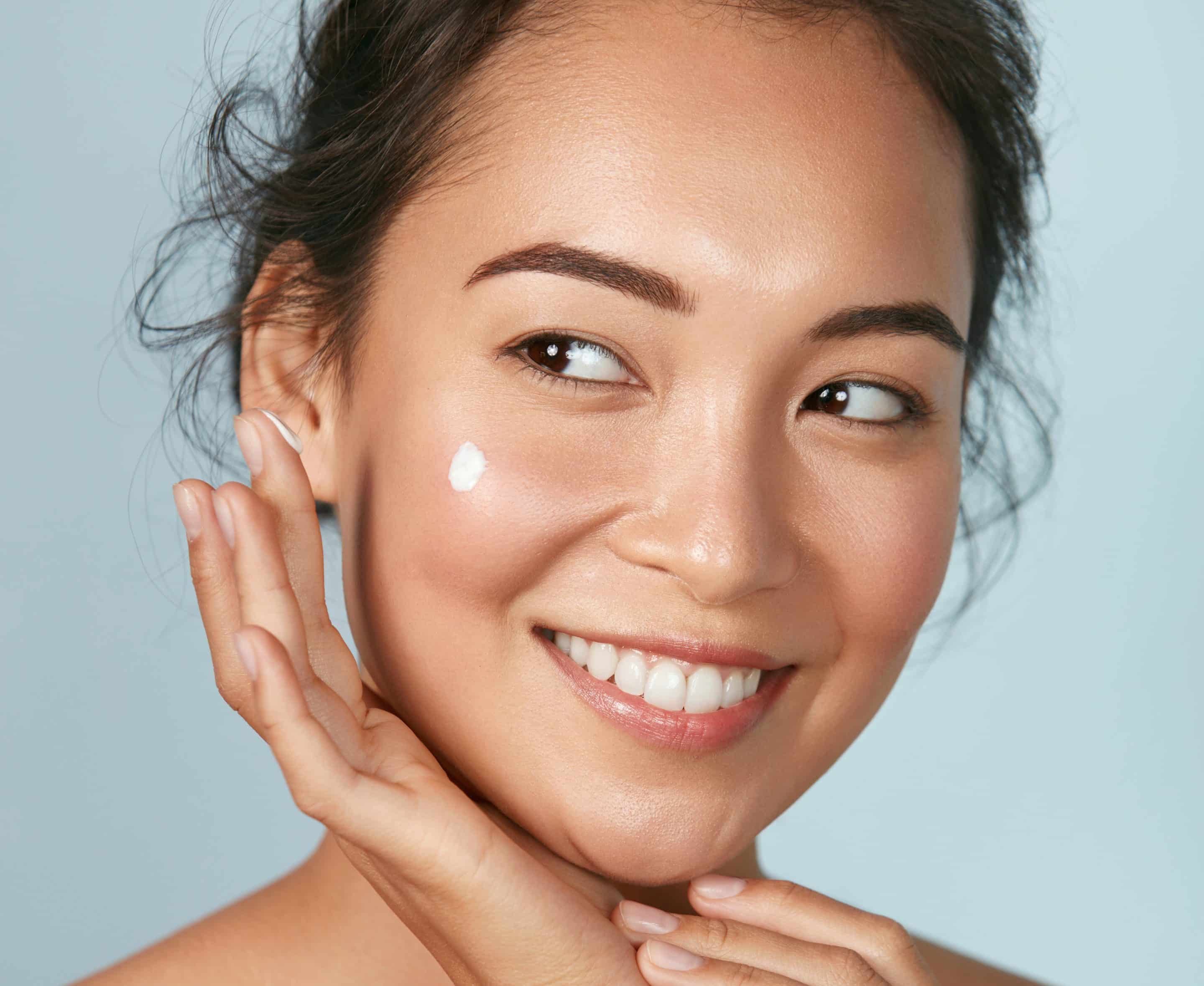 Woman  applying cosmetic cream on clean hydrated skin portrait