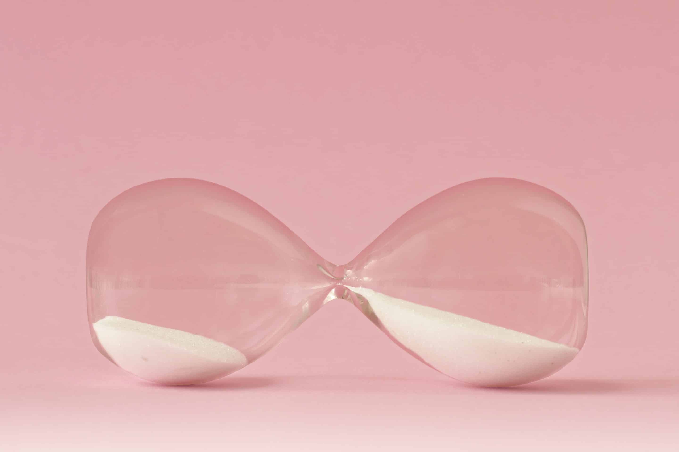 Hourglass,Lying,On,Pink,Background,-,Concept,Of,Time,And